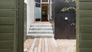 Un sendero de madera que conduce a un edificio moderno con fachada oscura y entrada de vidrio.