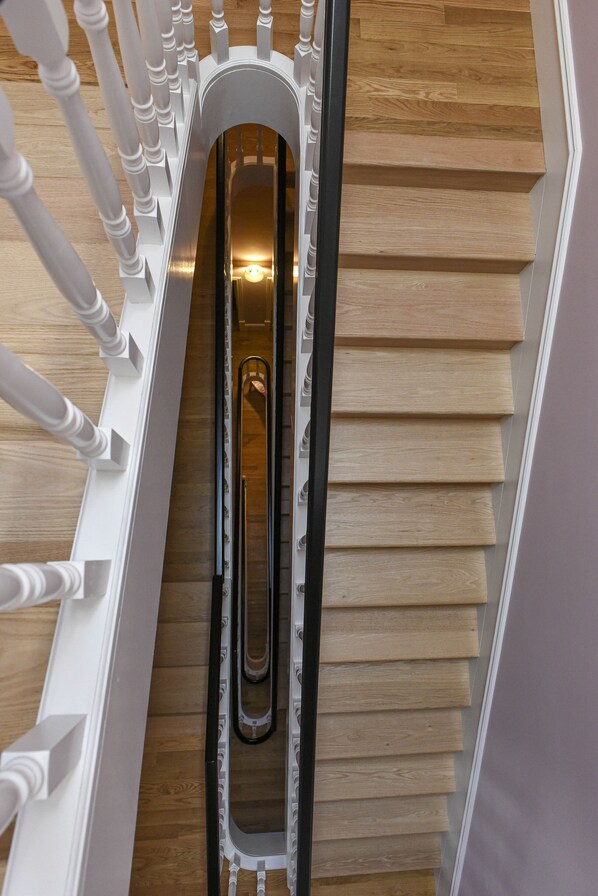 A wooden staircase with a metal handrail and white balusters.