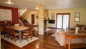 A spacious living area with a dining table, chairs, a stone pillar, a sofa, and a television. - Casa das Montanhas  (Campos do Jordão)