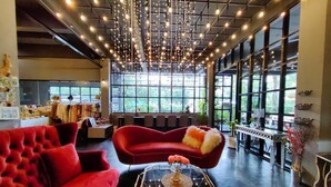 A spacious room with a red sofa, a glass coffee table, and a modern chandelier. - The Willow Phangan (Ko Pha-ngan)