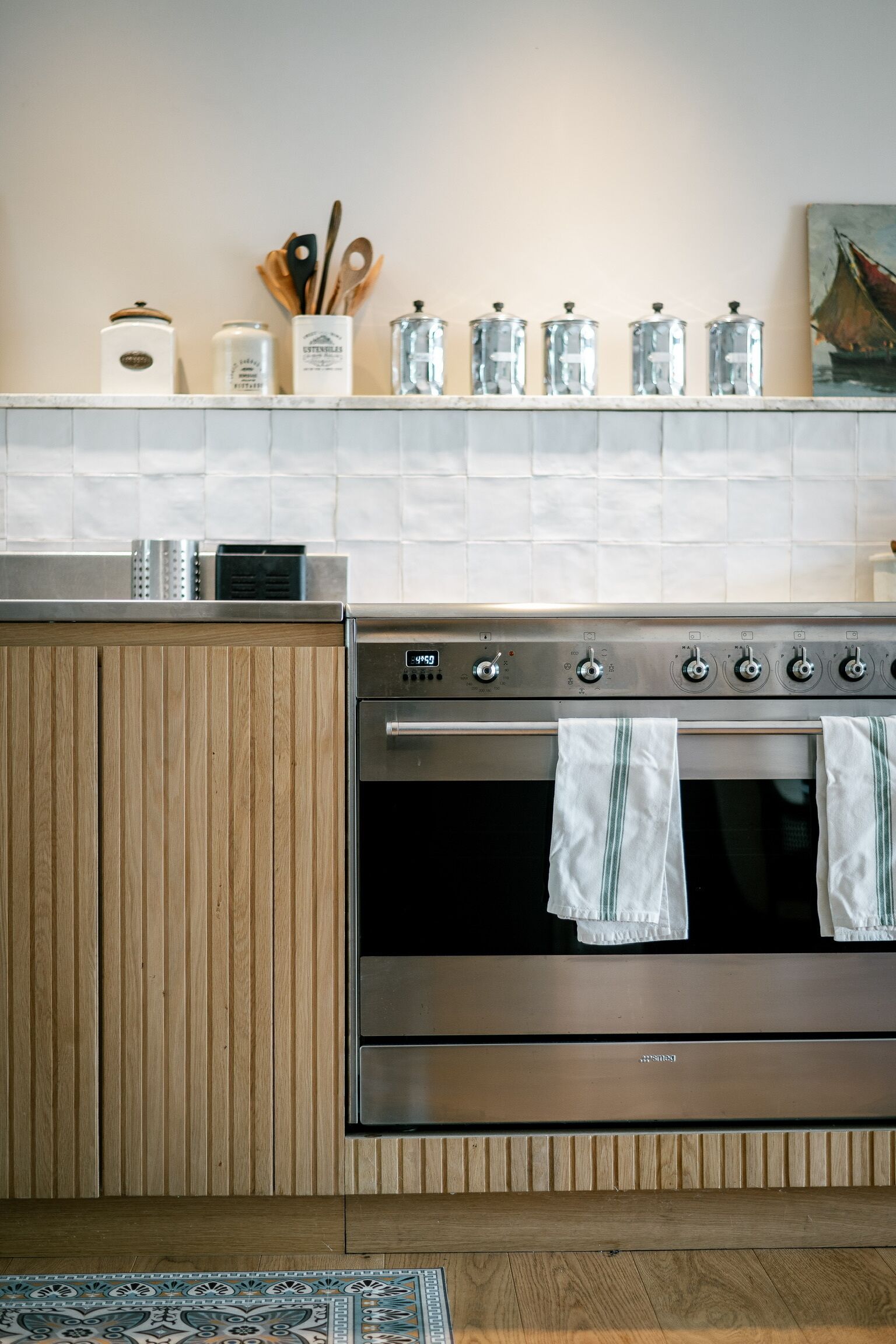 Uma cozinha com forno de aço inoxidável, armários de madeira e painel de azulejos.