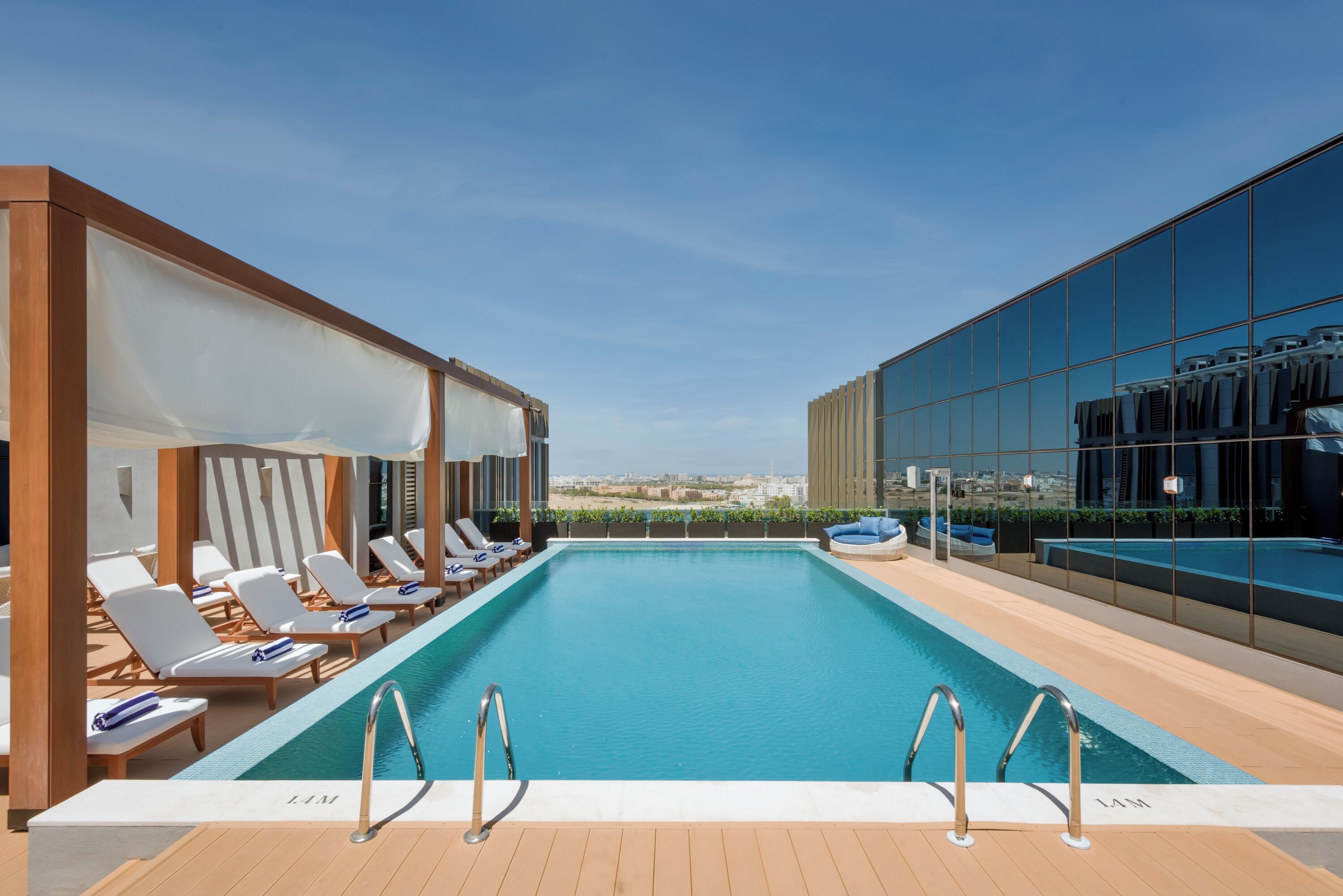 A rooftop swimming pool with lounge chairs and a view of the city.