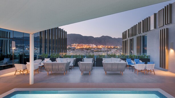 A rooftop pool area with lounge chairs and a view of a cityscape and mountains. - Intercityhotel Bawshar Muscat (Muscat)