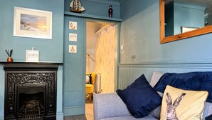 Una habitación con chimenea, un sofá con un cojín de conejo y un espejo en la pared.
