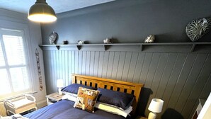 Un dormitorio con cama de madera, mesita de noche, cómoda y ventana con persianas.