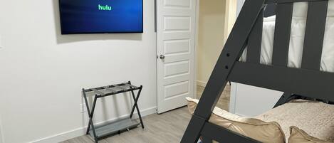 Ein Schlafzimmer mit Etagenbett, einem Fernseher, der 'hulu' anzeigt, einer Tür und einem kleinen Tisch.
