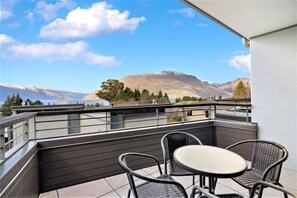 Een balkon met een tafel en stoelen, met uitzicht op een bergachtig landschap.