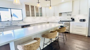 A modern kitchen with a large island, white cabinetry, and hanging pendant lights. - Minutes to Old Town · Resort Pool · 3 En Suites (Phoenix)