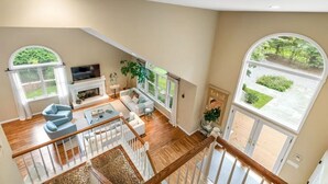 A spacious living area with a fireplace, comfortable seating, and large windows offering views of the outdoors. - Summer in Bridgehampton beautiful home minutes from Bridgehampton and Sag Harbor (Bridgehampton)