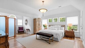 A spacious bedroom with a large bed, a bench, a dresser, and a chair. - Summer in Bridgehampton beautiful home minutes from Bridgehampton and Sag Harbor (Bridgehampton)
