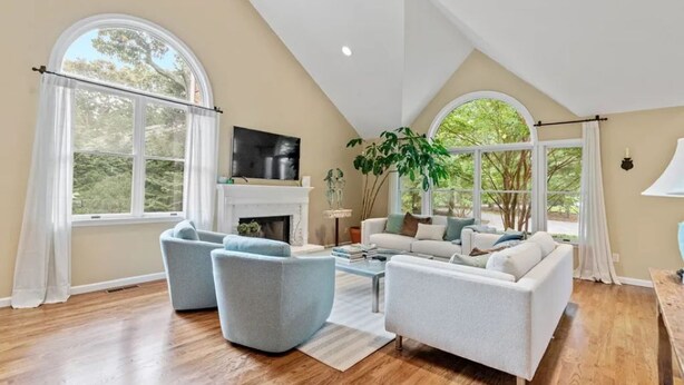 A spacious living room with a fireplace, two sofas, a coffee table, and large windows offering a view of the outdoors. - Summer in Bridgehampton beautiful home minutes from Bridgehampton and Sag Harbor (Bridgehampton)