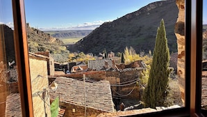 A view from a window overlooking a valley with traditional buildings and a mountain in the background. - El Bulín de Patones (Patones)