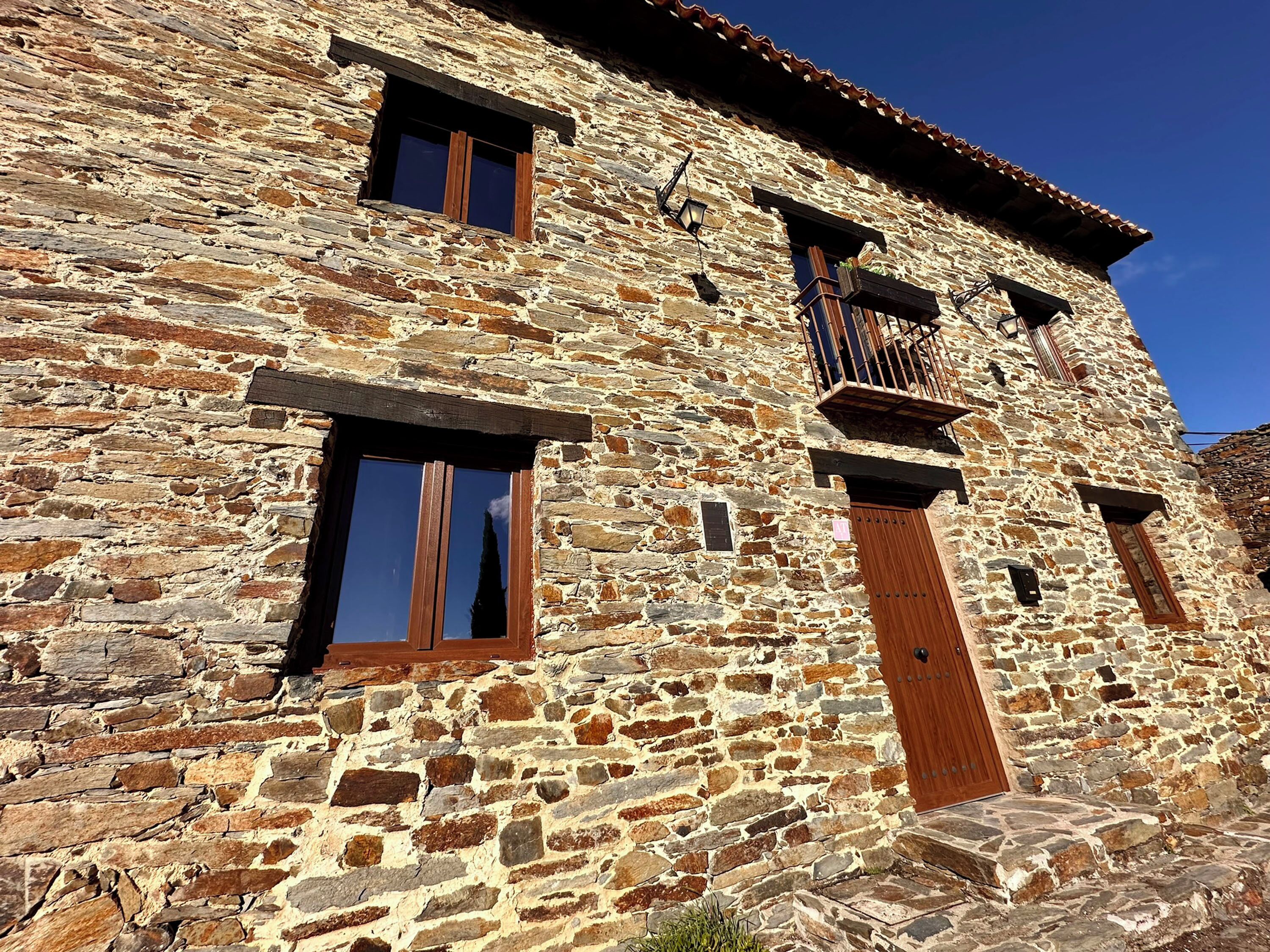 Un edificio de piedra con dos ventanas y una puerta de madera.