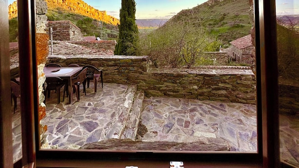 A stone patio with a table and chairs, overlooking a mountainous landscape with a clear sky. - El Bulín de Patones (Patones)
