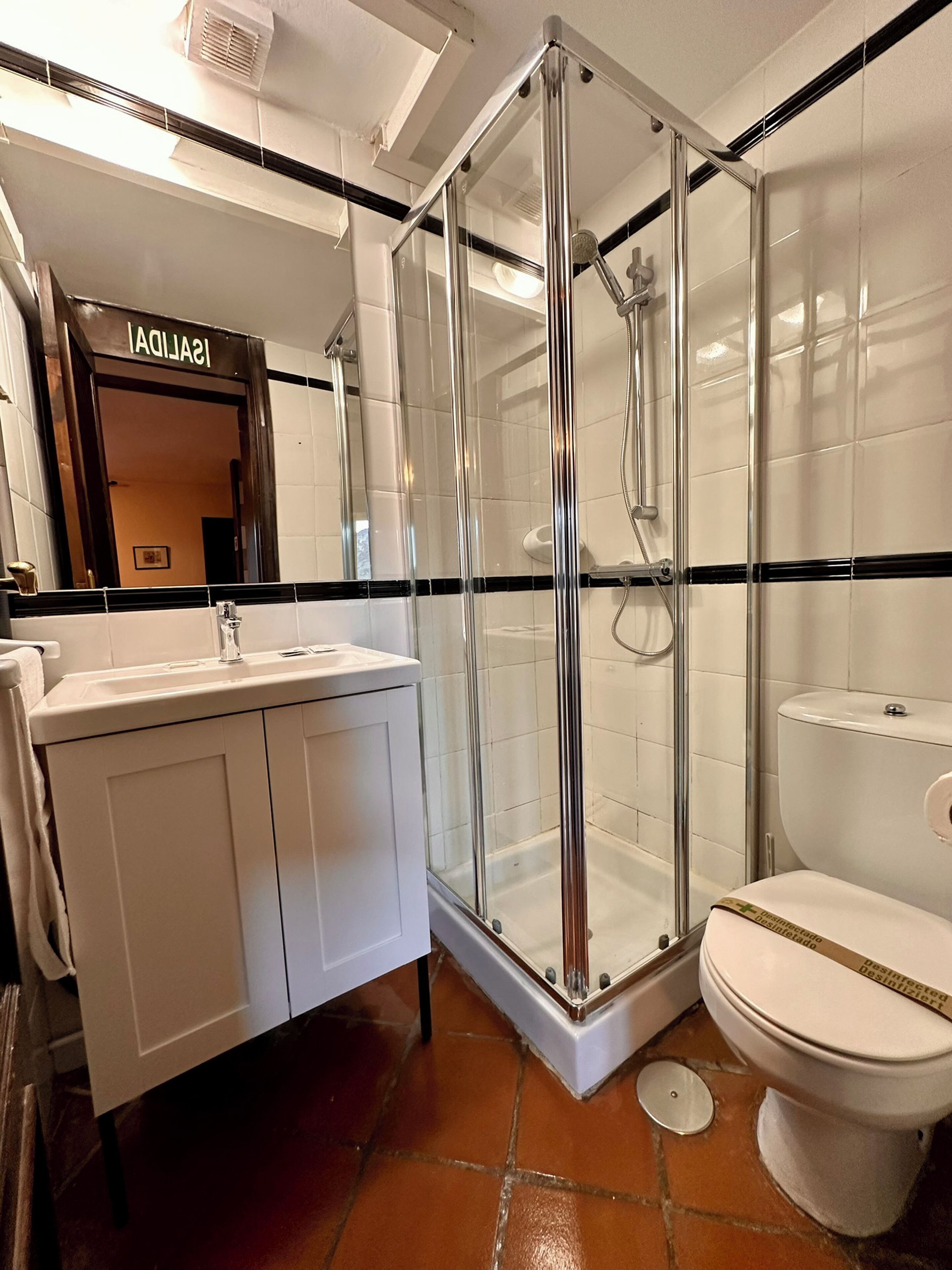 A modern bathroom with a glass-enclosed shower, a white sink, and a toilet.