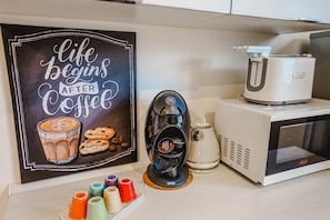 A kitchen counter with a coffee machine, a microwave, and a decorative sign that reads "life begins after coffee." - LA PIAZZETTA - TUSCANYINSTYLE (Pietrasanta)