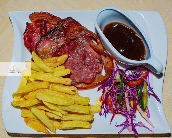 Un plato con tocino, papas fritas y una ensalada.