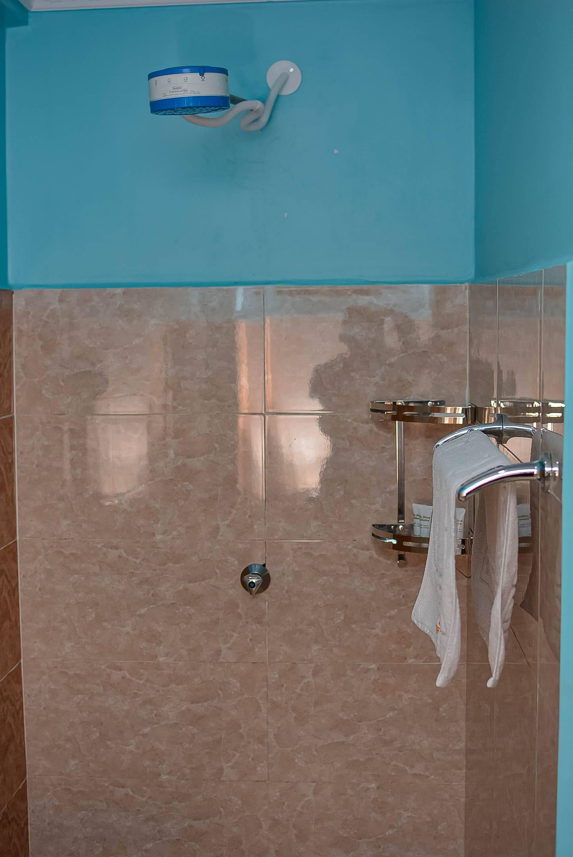 A bathroom with a blue wall, a towel rack with a towel, and a toilet paper holder.