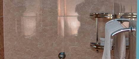 A bathroom with a blue wall, a towel rack with a towel, and a toilet paper holder.