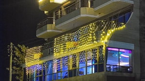Un edificio de varios pisos con balcones y un corredor cubierto decorado con guirnaldas luminosas.