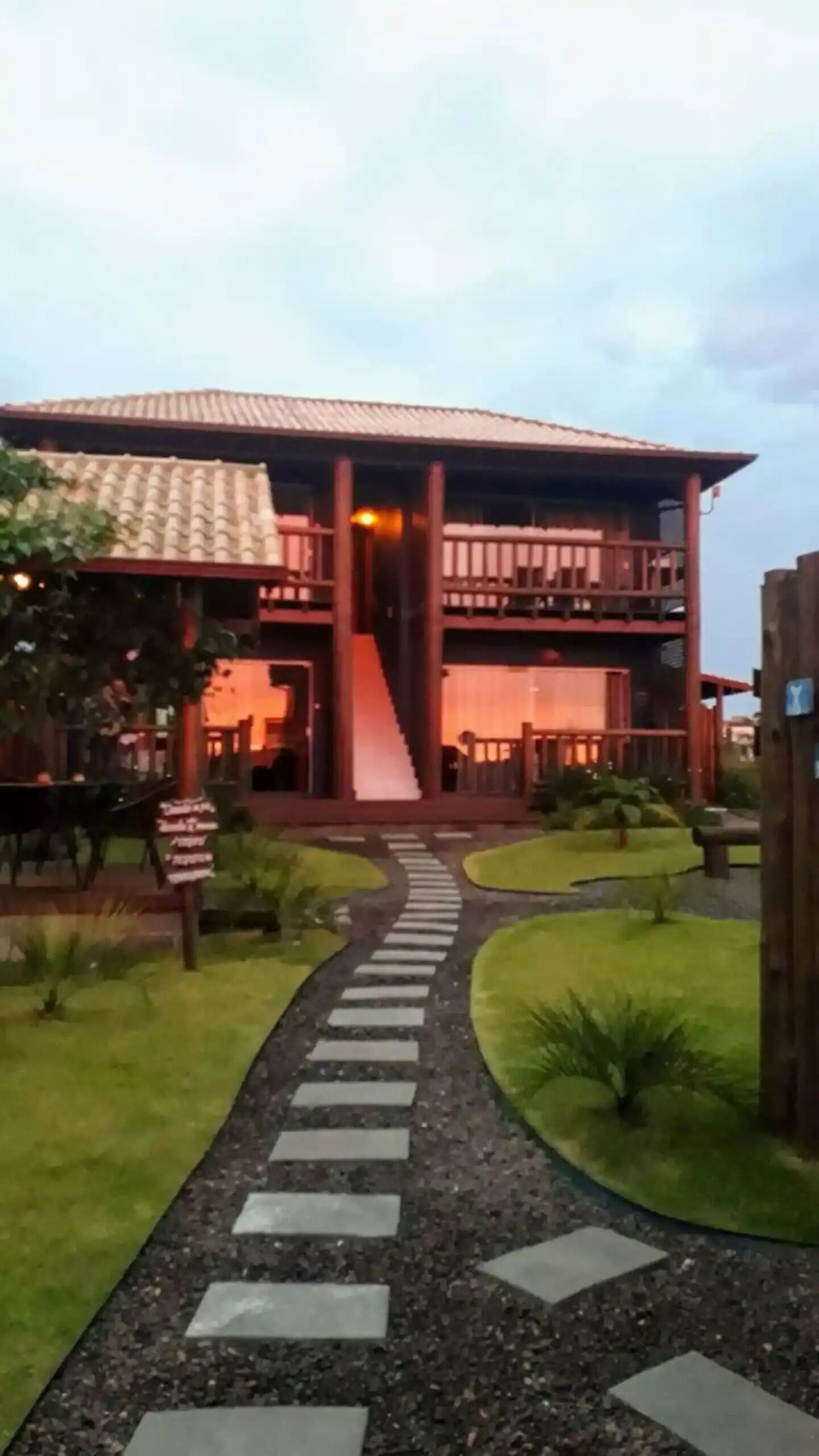 A building with a central staircase, a covered walkway, and a garden area with a pathway leading to the entrance.