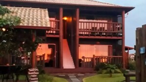 A building with a central staircase, a covered walkway, and a garden area with a pathway leading to the entrance. - Altos da Lagoa-praia do Rosa, Ibiraquera -studio 3 (Imbituba)