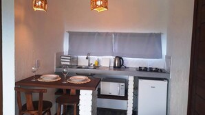 A compact kitchen with a dining area, featuring a small refrigerator, microwave, and a sink. - Altos da Lagoa-praia do Rosa, Ibiraquera -studio 3 (Imbituba)