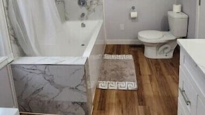 Une salle de bain avec une douche en marbre, des toilettes et un lavabo.