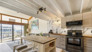 A modern kitchen with a large island, stainless steel appliances, and a view to the outside. - Top floor condo with sunset Gulf views (Cedar Key)