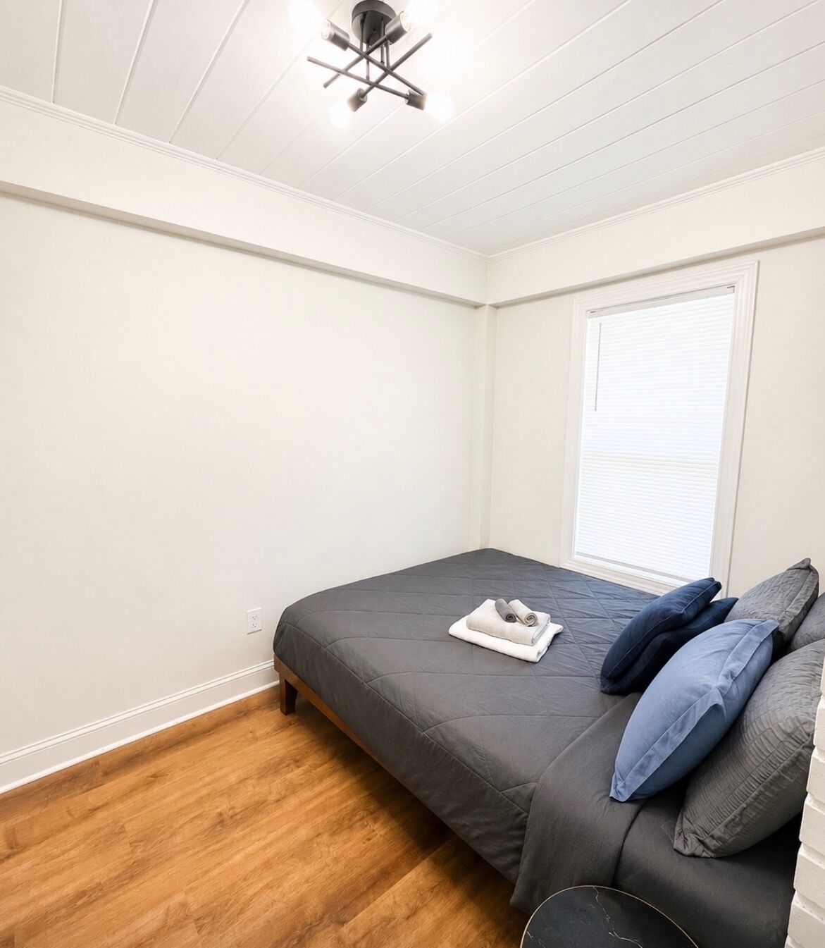 A bedroom with a bed, a window, and a ceiling fan.