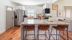 A modern kitchen with a large island, stainless steel appliances, and a view of the outdoors. - The Georgia Peach (Forest Park)