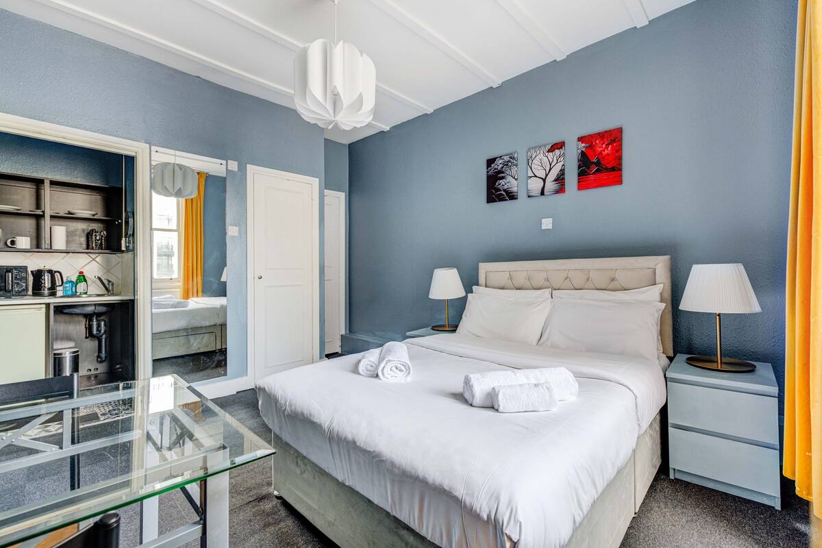 A hotel room with a bed, bedside tables, a desk, and a wardrobe.