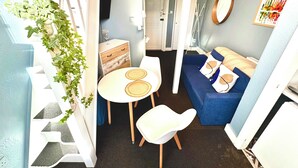 A compact living space with a dining area, a sofa, and a staircase. - Kensington Gardens (London)