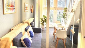 A modern living room with a sofa, a dining table, and a large window. - Kensington Gardens (London)