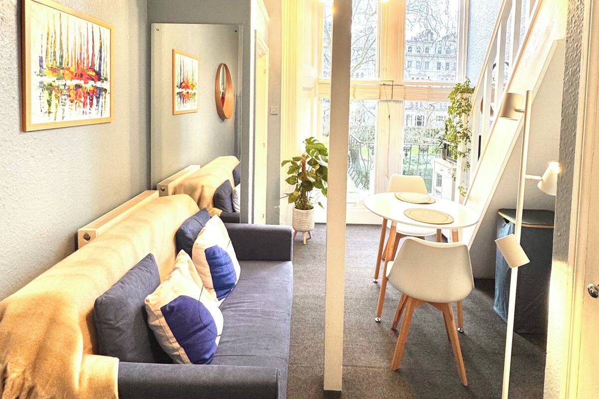 A modern living room with a sofa, a dining table, and a large window.