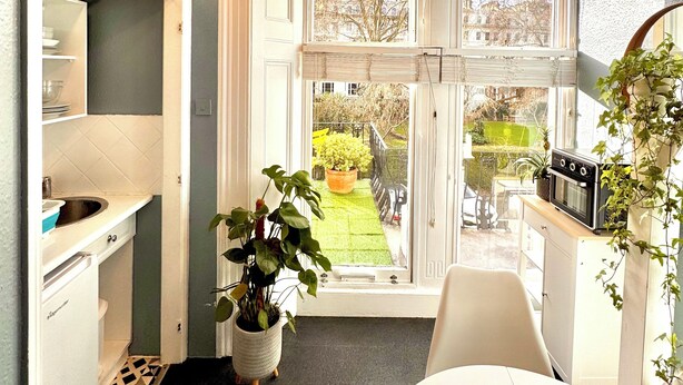 A modern kitchen with a large window, a built-in oven, and a potted plant. - Kensington Gardens (London)