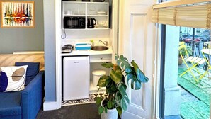 A compact living space with a kitchenette, a dining area, and a view through a large window. - Kensington Gardens (London)