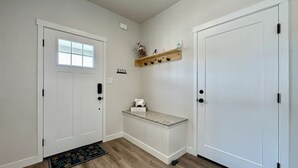 A hallway with a white door, a small bench, a shelf with keys, and a doormat. - New Built - Clean - Comfort (Grand Junction)