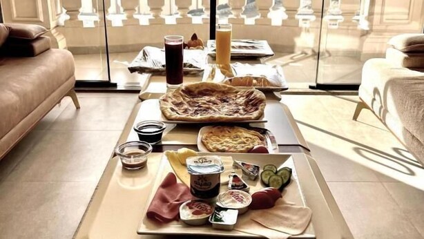 A dining table with food and drinks, a candle, and a view of pyramids through large windows. - Pyramids Charm (Giza)