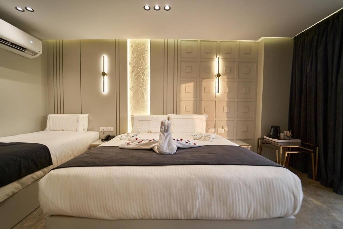 A hotel room with two beds, a minibar, and a wall-mounted air conditioner.