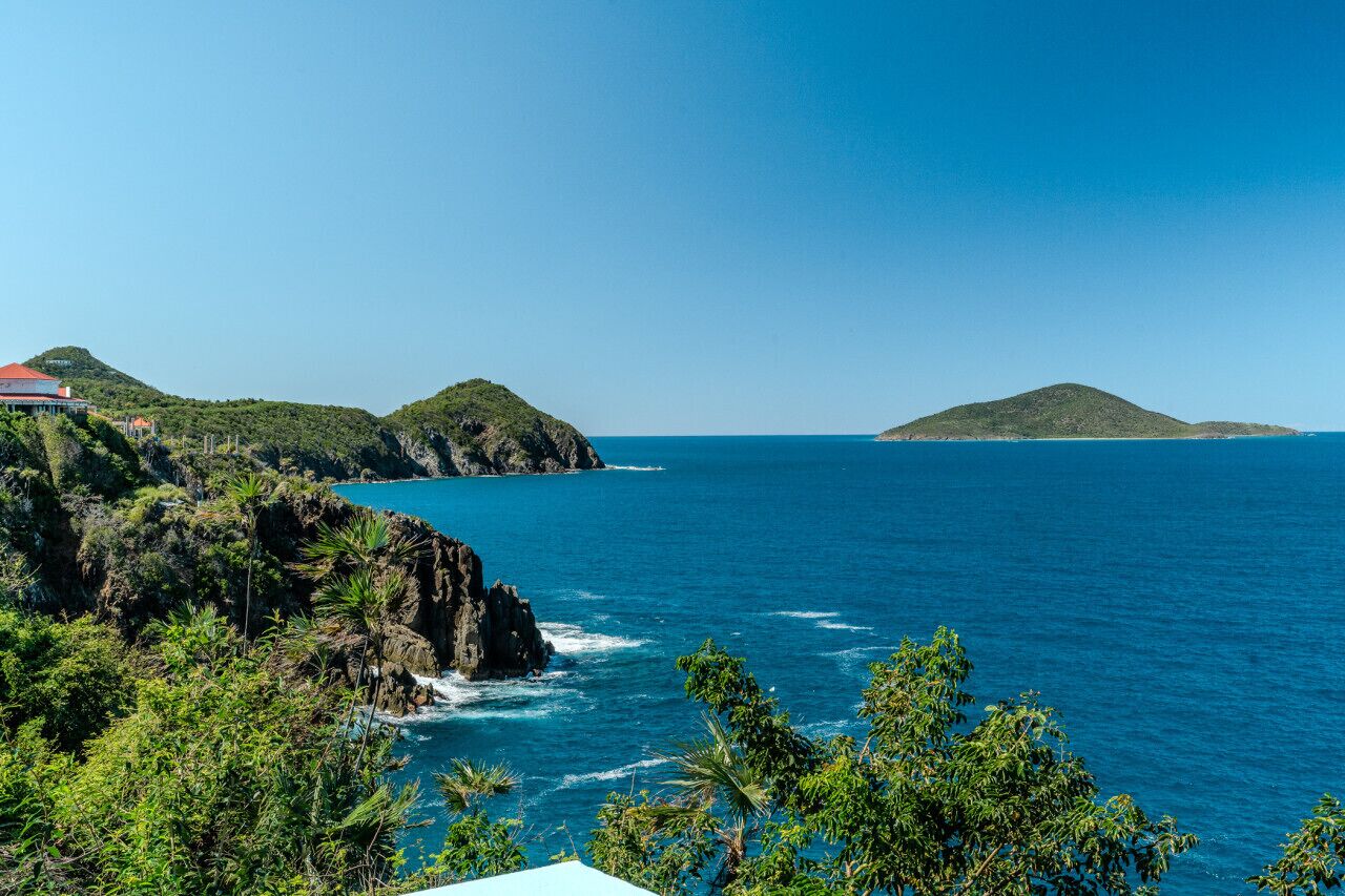 Un paysage côtier caractérisé par des falaises rocheuses, une mer d’un bleu limpide et une végétation luxuriante.