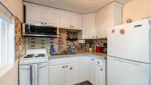 A kitchen with white cabinets, a stove, a microwave, and a refrigerator.