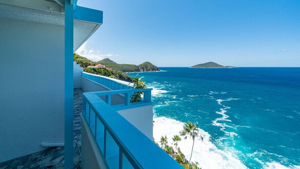 A balcony with a view of the ocean and distant islands.