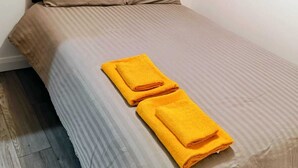 Ein Bett mit gestreifter Bettdecke, zwei Kissen und zwei gefaltete Handtücher.
