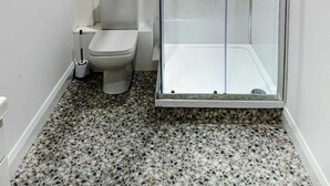 Ein kleines, modernes Badezimmer mit einer gläsernen Duschkabine, Toilette und Bidet.