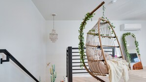 A modern room with a hanging chair, a staircase, and a mural of cacti. - Jacuzzi Hot Tub + Zion Base Camp @La Chona (Hurricane)