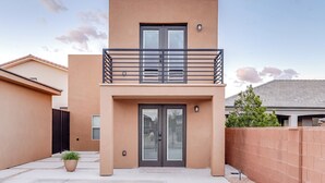 A modern two-story building with a balcony, a large door, and a small window. - Jacuzzi Hot Tub + Zion Base Camp @La Chona (Hurricane)