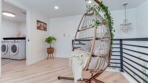 A modern living room with a hanging chair, a washing machine, a potted plant, and a chandelier. - Jacuzzi Hot Tub + Zion Base Camp @La Chona (Hurricane)