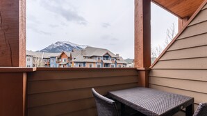 Ein Balkon mit Korbmöbeln, Blick auf bunte Häuser und ein Berg im Hintergrund.