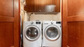 Un lavadero con dos lavadoras de carga frontal y armarios de madera arriba.
